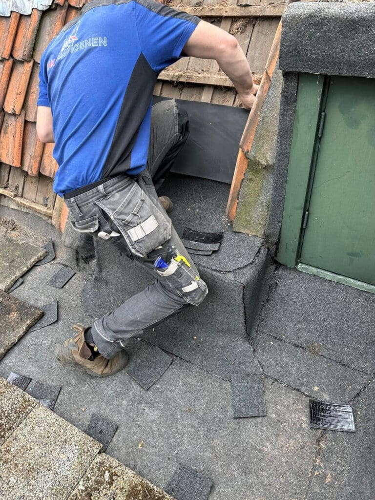 Dakdekker werkt aan dakgoot langs woning