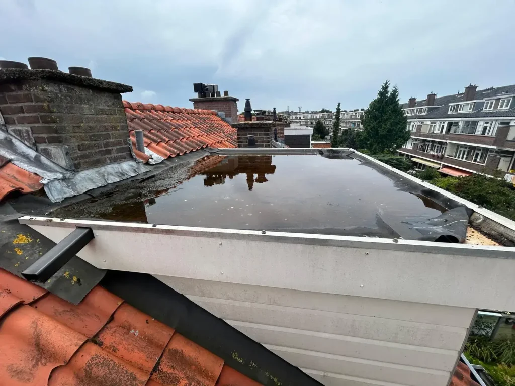 Plat dak met ernstige waterophoping door slechte afwatering en versleten dakbedekking in Rotterdam