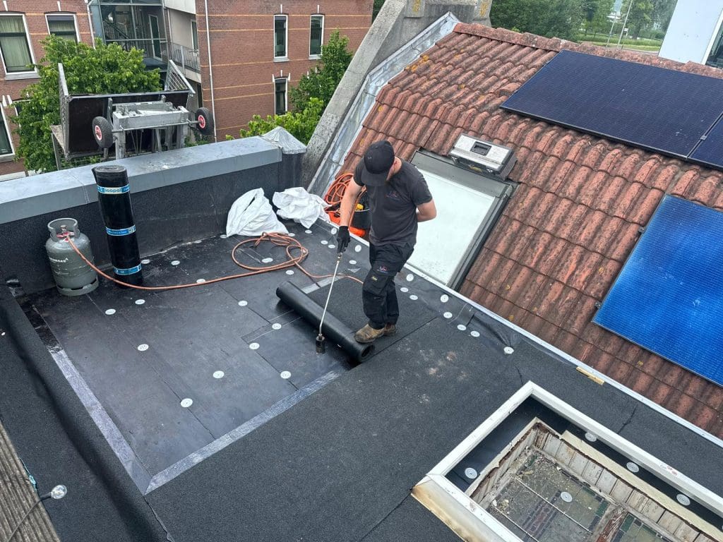 Plat dak met isolatie, bitumen en vernieuwd dakraam