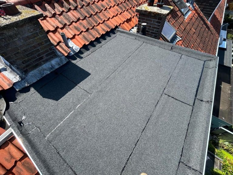 Gerenoveerd plat dak van een dakkapel met nieuwe bitumen dakbedekking en nette aansluitingen op het pannendak.