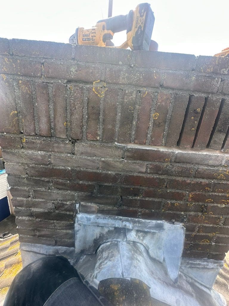 Bakstenen opstand van een dakkapel met vernieuwde dakafdichting tijdens renovatie van het platte dak.