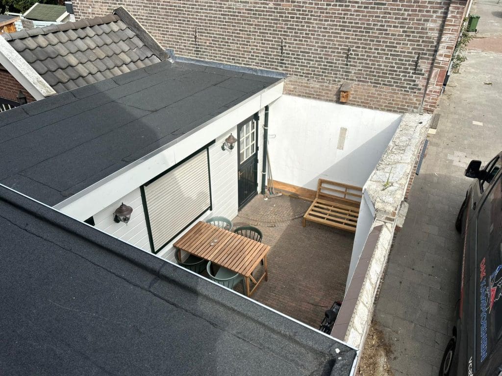 Hoekwoning met wolfdak, rode dakpannen en donkergroene dakranden in een woonstraat