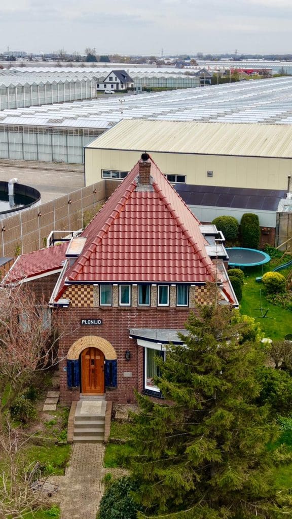 Vrijstaande bakstenen woning met rood pannendak in schilddakvorm, gezien van bovenaf in een woonwijk