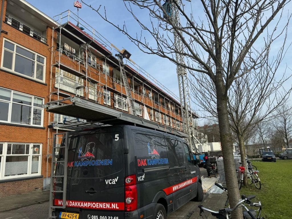 Steigers langs een appartementencomplex met werkzaamheden aan het schuine dak.