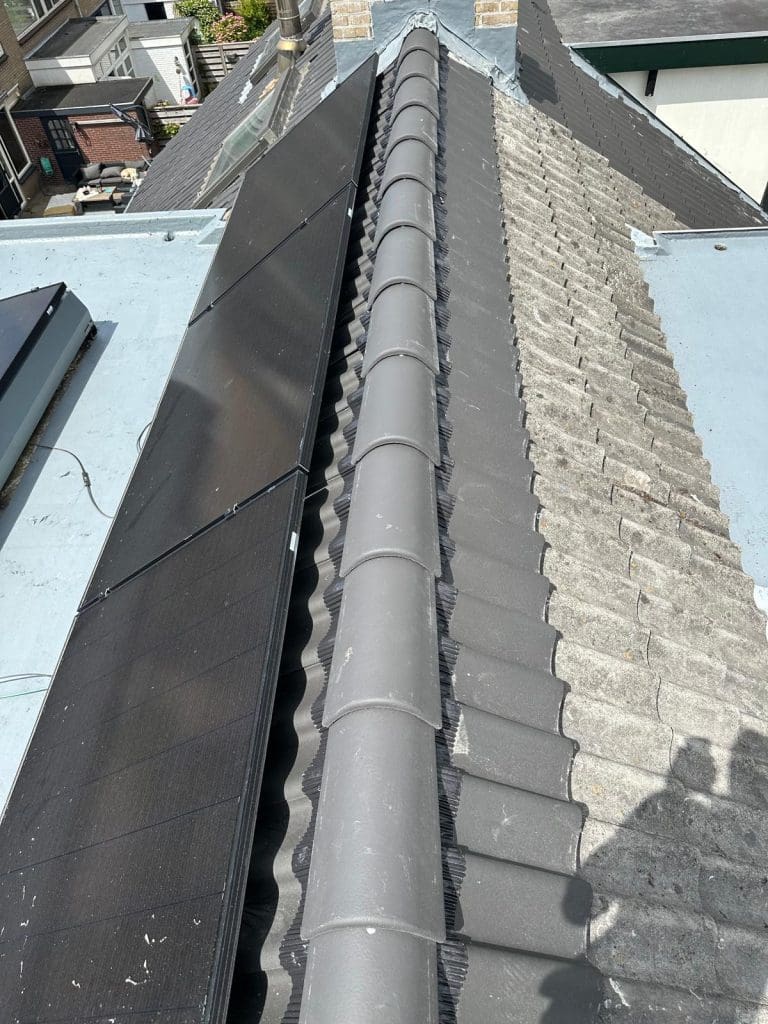 Bouwkraan hijst materialen naar het schuine dak van een appartementencomplex met steigers.